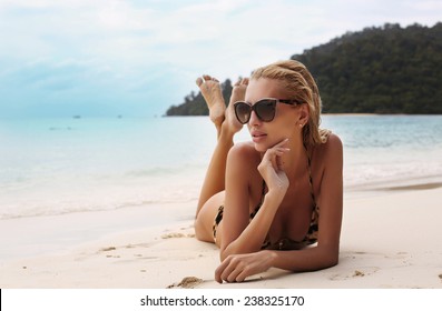 fashion outdoor photo of sexy beautiful woman with long blond hair wearing elegant bikini and sunglasses,enjoying her vacation on island  