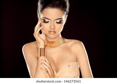  Fashion photo of beautiful brunette woman posing in golden jewelry isolated on black background