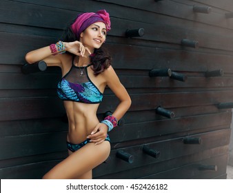 Fashion photo of beautiful tanned woman with perfect body and hair in bikini posing in sunny day over the wall.Sensual young girl enjoying vacation on luxury villa. Colorful filter,tan skin tone