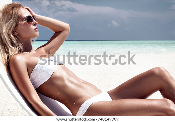 熱帯の島の白い椅子に座り 完璧なビーチでくつろぐ 金髪の美しい日焼けした女性のファッション写真 の写真素材 今すぐ編集