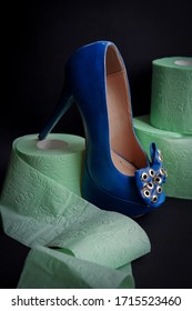 Fashion Photo Of High Heel Bright Blue Shoe Surrounded By Rolls Of Toilet Paper Isolated On Dark Black Background Showing Modern Social Problems