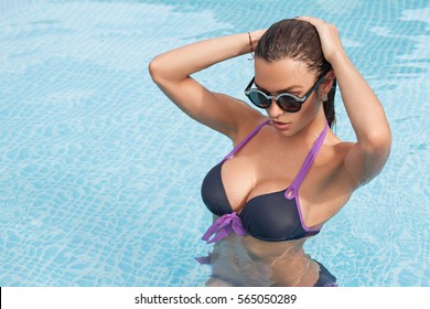 fashion photo of sexy beautiful girl with brunette hair in elegant bikini posing and takes a sunbath in the swimming pool
