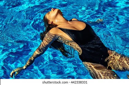 fashion photo of sexy hot beautiful girl model with dark hair in black swimwear swimming on back in swimming pool with red lips