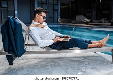 Fashion photo of smart man with a laptop relaxing on sun lounger near pool - Powered by Shutterstock