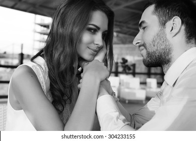 Fashion photo of two young beautiful lovers wearing elegant clothes sitting in a restaurant and looking at each other