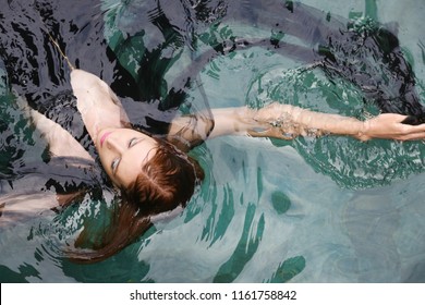 Fashion Photo Of Woman Wrapped In Black Sheer Fabric In Swimming Pool