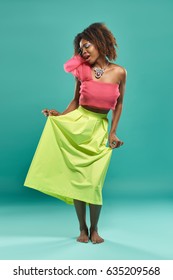 Fashion photo of young african girl posing over green background in studio
