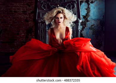Fashion photo of young magnificent woman. Running towards camera. Seductive blonde in red dress with fluffy skirt