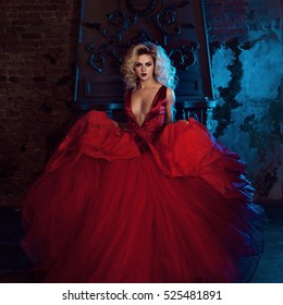 Fashion photo of young magnificent woman. Running towards camera. Seductive blonde in red dress with fluffy skirt