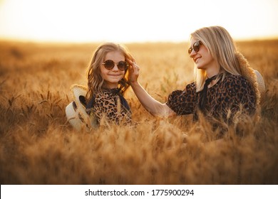 Fashion Photo Of A Young Mother And Her Daughter In Leopard Print Dress And Staw Hat, Same Sunglasses At The Wheat Field On A Sunny Day