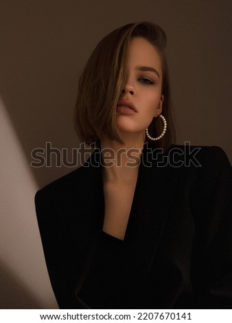 Fashion photography. A beautiful girl in a black jacket with a dramatic light. Imitation grain film photography. High quality photo