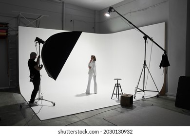 Fashion photography in a photo studio. Professional male photographer taking pictures of beautiful woman model on camera, backstage - Shutterstock ID 2030130932