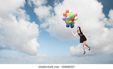 Fashion Photoshoot With  A Beautiful Young Woman Flying With Balloons Over The Sky