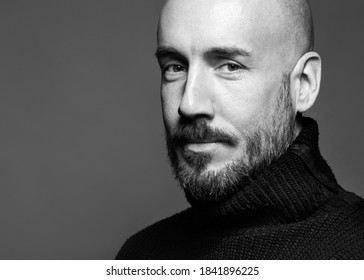 Fashion Portrait Of A 40-year-old Man Standing Over A Light Gray Background In A Black Sweater. Close Up. Classic Style. Bald Shaved Head. Copy-space. Studio Shot