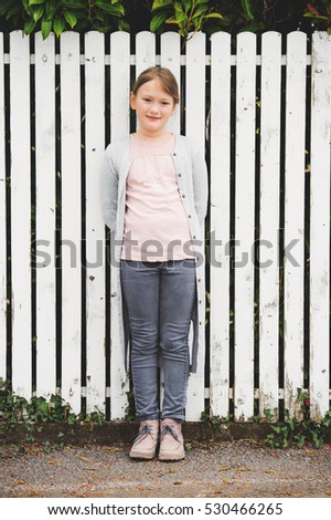 Fashion portrait of 7-8 year old little pretty girl wearing grey clothes, cardigan and trousers