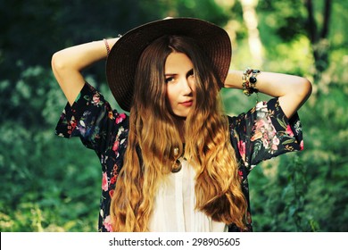 Fashion Portrait Of Beautiful Hippie Young Woman Wearing Boho Chic Clothes And Summer Hat Outdoors. Soft Warm Vintage Color Tone. Artsy Bohemian Style.