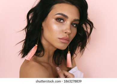 fashion portrait of beautiful young woman with dark hair and glowing skin posing in studio