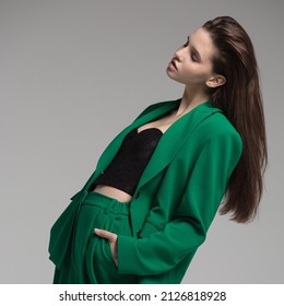 Fashion portrait of a charming girl dressed in a green suit. Gray background. - Powered by Shutterstock