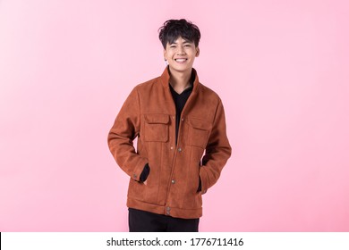 Fashion Portrait Of Confident Handsome Young Asian Man With Keeping Hands In Pockets Of Pocket The Side Eyes Looking At Camera In Isolated On Pink Blank Copy Space Studio Background.