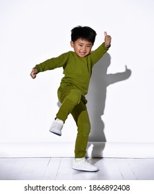 Fashion portrait of cute little kid boy in stylish green tracksuit dancing break against white studio wall. The concept of sports and healthy activities for the modern child.