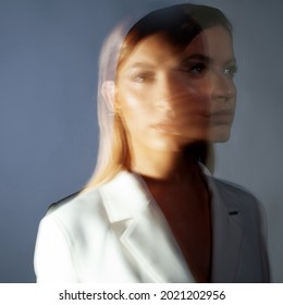 Fashion portrait with the effect of blurring in motion at a long shutter speed, distortion of the model's face. Young stylish woman in a white jacket