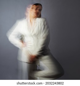 Fashion Portrait With The Effect Of Blurring In Motion At A Long Shutter Speed, Distortion Of The Model's Face. Alter Ego, Soul Movements, Concept. Young Stylish Woman In A White Jacket