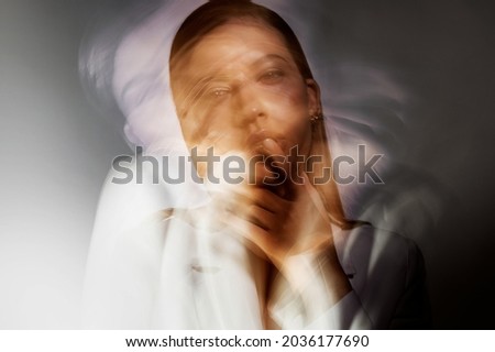 Fashion portrait with the effect of blurring in motion at a long shutter speed, distortion of the model's face. versatility of the personality is a complex mindset, Young stylish woman in white jacket