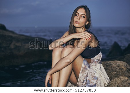 Fashion portrait of a girl model at night on the beach