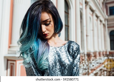Fashion portrait of gorgeous girl with blue dyed curly hair long. The beautiful evening cocktail dress. Professional makeup and hair styling. Vintage old aristocratic building. Close-up