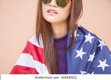 Fashion Portrait Of Hipster Asian Woman Wearing Sunglasses And Holding The American Flag.