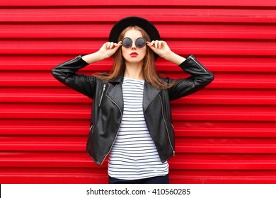 Fashion portrait pretty woman in black rock style over red background