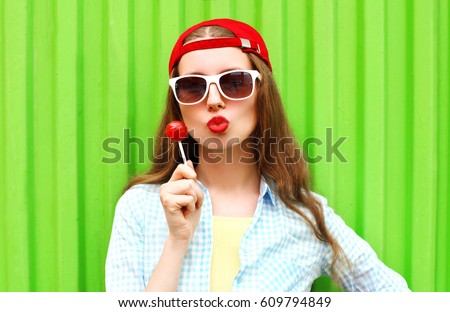 Fashion portrait pretty woman with lollipop candy over green colorful background