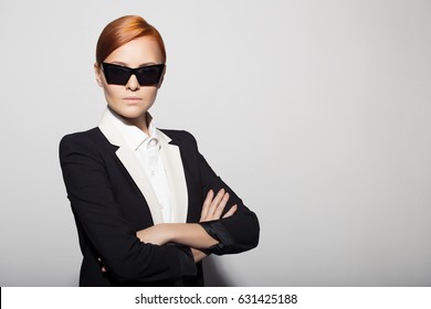 Fashion Portrait Of Serious Woman Dressed As A Secret Agent Or Spy. Gray Background.