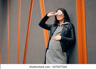 Fashion Portrait Of A Stylish Pregnant Woman. Cool Mother To Be Wearing Hooded Dress And Leather Jacket
