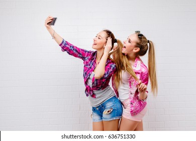 Fashion portrait of two friends posing. modern lifestyle.two stylish sexy hipster girls best friends ready for party.Two young girl friends standing together and having fun. Taking selfie