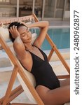 Fashion Portrait. Woman In Black Swimsuit Relaxing On Deck Chair By Swimming Pool
