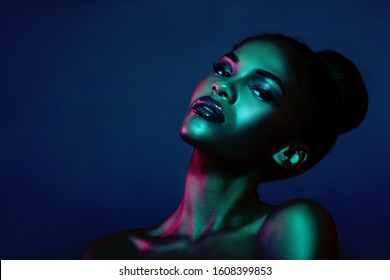 Fashion Portrait Of A Woman With Creative Lighting And Beautiful Makeup. Blue Background. Black Girl In Blue Light. Trendy Color Background     