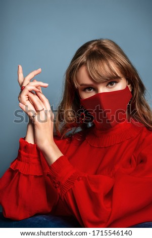 Fashion portrait of woman wearing trendy luxury total red outfit including designer protective face mask. Elegant look during quarantine of coronavirus pandemic. Model posing in studio