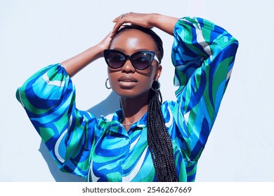 Fashion portrait of young African Nigerian model posing with her arms up having a braided hair style wear black classic shaped sunglasses  - Powered by Shutterstock