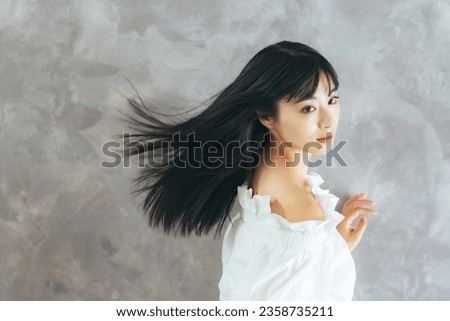 Fashion portrait of young Asian attractive woman blowing her long black hair. Hair care concept. cosmetics. Beauty salon.