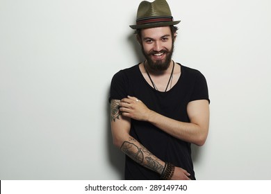 fashion Portrait of young bearded man. Smiling Hipster boy.handsome man in hat.Brutal bearded boy with tattoo
