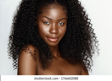 Fashion portrait of young beautiful african american woman with curly hair against gray background 