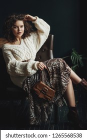  Fashion Portrait Of Young Beautiful Confident Woman Wearing Cozy White Knitted Sweater, Animal Print Skirt, Belt, Holding Small Brown Bag, Posing At Loft Interior