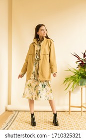 Fashion Portrait Of Young Beautiful Woman Wearing Autumn Spring Outfit. Hipster Girl Wearing Modern Trench Coat And Dress