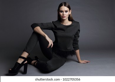 Fashion Portrait Of Young Elegant Woman. Grey Sweatshirt And Pants, Grey Background, Black Shoes, Studio Shot