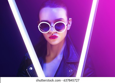 Fashion portrait of young elegant woman in sunglasses. Colored background, studio shot