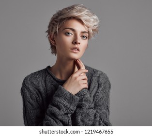 Fashion portrait of young woman with blond short hair isoalted on gray background