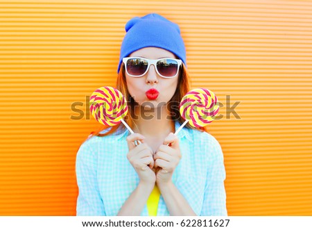 Fashion portrait young woman and lollipop is having fun over colorful orange background