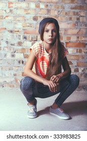 Fashion Pre Teen Girl Dressed In Sports Wear And Sneakers Posing Over Brick Wall