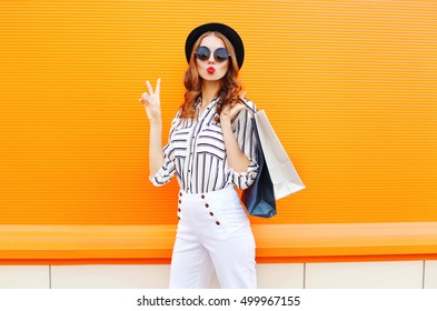 Fashion Pretty Cool Young Girl With Shopping Bags Wearing A Black Hat White Pants Over Colorful Orange Background